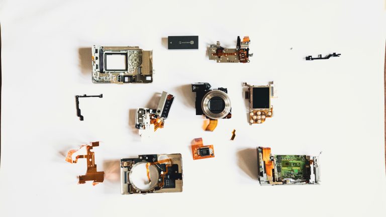 A camera fully disassembled into its individual components on a white surface