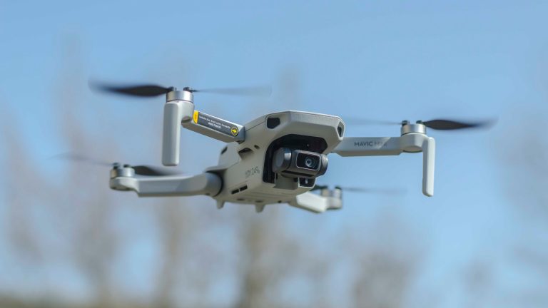 DJI Mavic Mini drone in flight against a clear blue sky