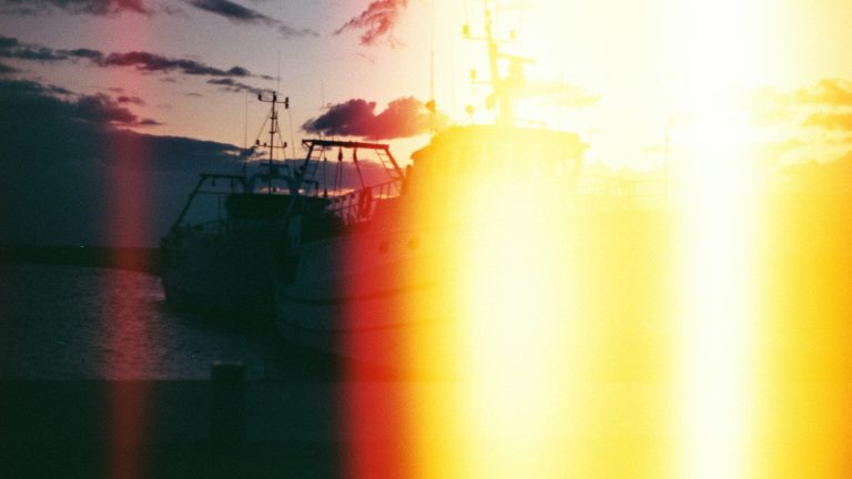 Sunset light leak and halation over a boat, shot on film