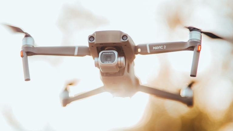 DJI Mavic 2 drone hovering, front view showing its Hasselblad camera and folded arms
