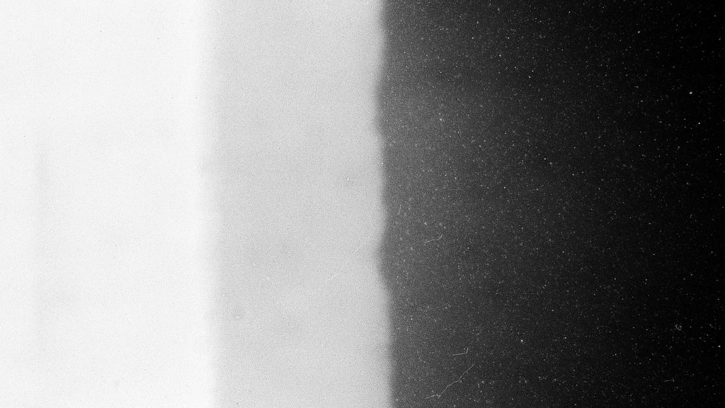 Close-up of high-contrast black and white film grain texture with scratches and dust