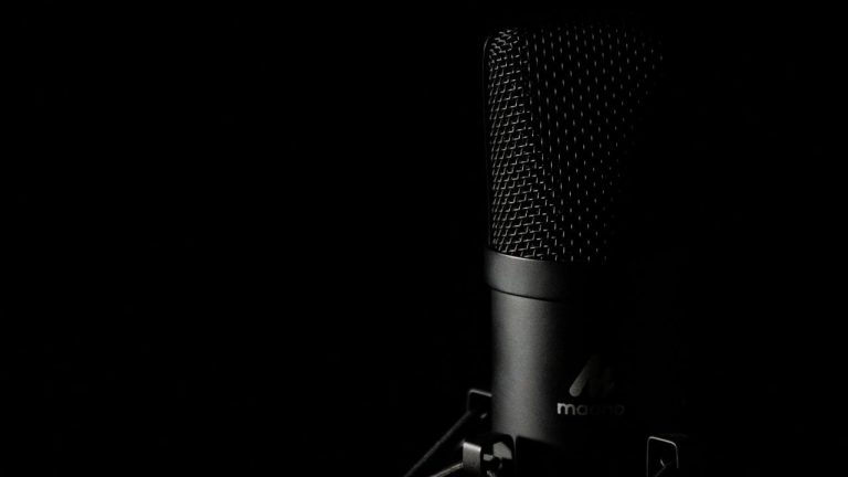 Studio condenser microphone with pop filter against dark background — representing AI voice generation for video creators