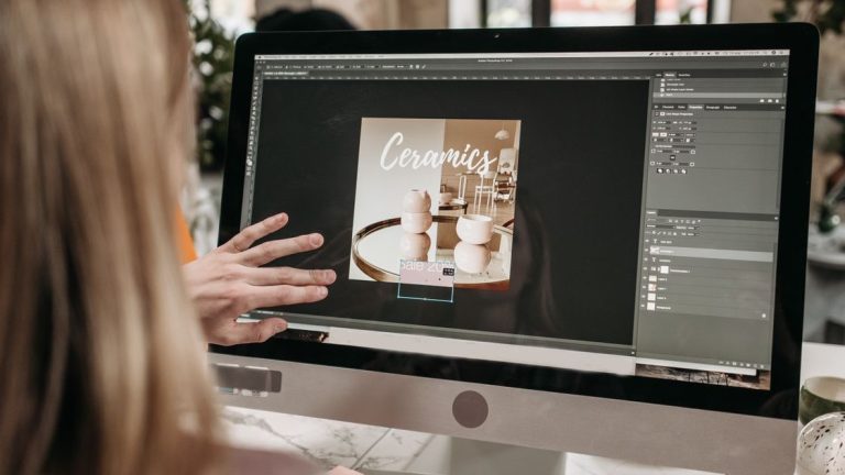 Graphic designer editing a promotional layout on an iMac in a design workspace